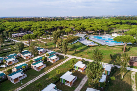 Luchtbeeld van een lodge met kleine huisjes, groene zones, bos en een groot openluchtzwembad.