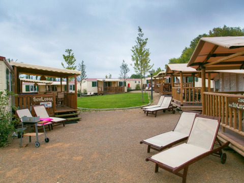 Vista de las cabañas SunLodge Aspen y tumbonas en el Camping Vilanova Park en España en un día nublado.