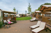 Zicht op de SunLodge Aspen-hutten en ligzetels bij Camping Vilanova Park in Spanje op een bewolkte dag.