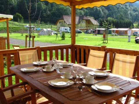 Buitenterras bij SunLodge Maple met een gedekte tafel, uitzicht op grasveld, tenten en natuur.