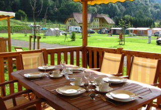 Buitenterras bij SunLodge Maple met een gedekte tafel, uitzicht op grasveld, tenten en natuur.