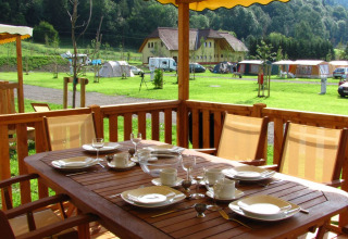 Zona de comedor exterior en SunLodge Maple, mesa puesta en terraza con vistas al césped y tiendas.