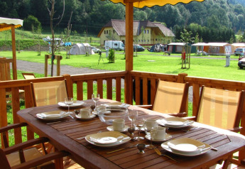 Espace repas extérieur à SunLodge Maple, table dressée sur terrasse avec vue sur pelouse et tentes.