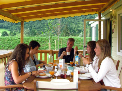 Vijf mensen ontbijten samen op het terras bij SunLodge Maple met zicht op groene heuvels.