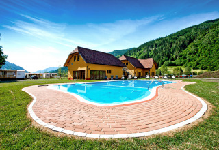 Piscina al aire libre en SunLodge Maple con colinas verdes y cielo azul de fondo, paisaje tranquilo.