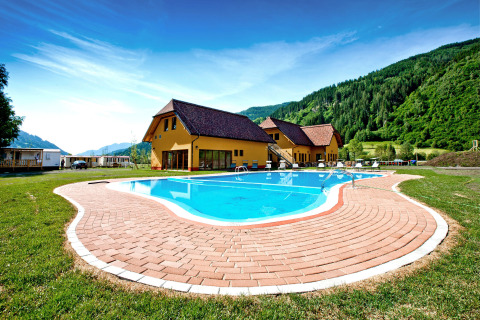 Udendørs swimmingpool foran SunLodge Maple med grønne bakker og blå himmel i baggrunden.