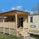 Et luksuriøst træhus med overdækket terrasse, trappe og solrigt vejr, perfekt til afslapning.