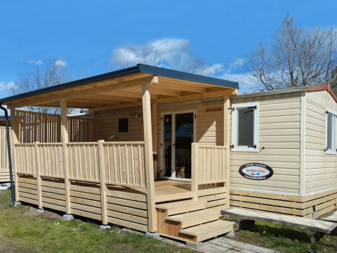 Un lodge de luxe en bois avec terrasse couverte et escalier, idéal pour un séjour détente au soleil.