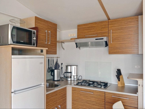 Modern kitchen at SunLodge Aspen Premium with wood cabinets, gas stove, microwave, and refrigerator.