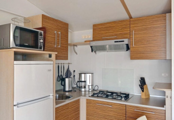 Cucina moderna al SunLodge Aspen Premium con armadi in legno, fornello a gas, microonde e frigorifero.