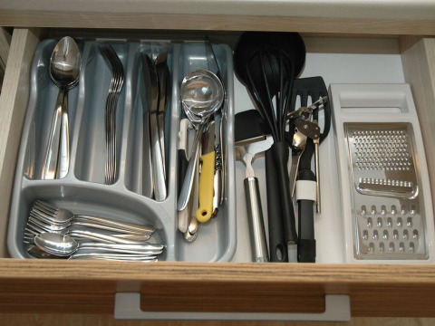 Cajón de cubiertos organizado con cucharas, tenedores, cuchillos y utensilios de cocina en un lodge en Italia.