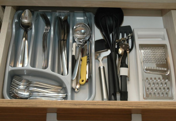 Tiroir à couverts organisé avec cuillères, fourchettes, couteaux et ustensiles de cuisine dans un lodge en Italie.