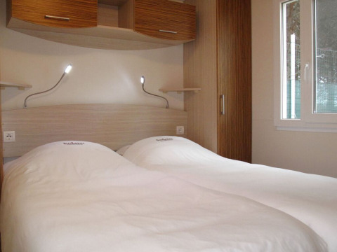 Værelse på SunLodge Aspen Premium med to enkeltsenge, hvide dyner, læselamper og moderne indretning.