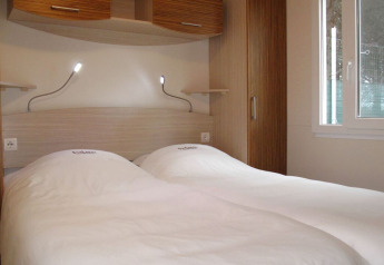 Camera al SunLodge Aspen Premium con due letti singoli, piumoni bianchi, lampade da lettura e arredo moderno.