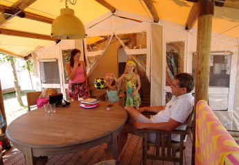 Famiglia che si rilassa e gioca con un pallone in una tenda safari SunLodge Jungle, Camping Vilanova Park, Spagna.