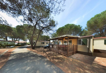 SunLodge Aspen au Camping Village Baia Blu La Tortuga en Italie, entouré de pins et d’allées boisées.