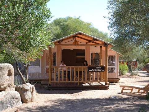 Udsigt til SunLodge Safari-hytte med to personer på terrassen ved Centro Vacanze Isuledda, Italien.