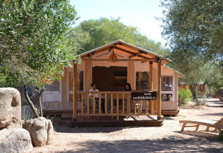 Udsigt til SunLodge Safari-hytte med to personer på terrassen ved Centro Vacanze Isuledda, Italien.