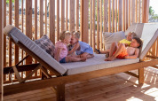 Vier kinderen amuseren zich op een groot houten ligbed bij SunLodge Catalpa, Camping Cisano/San Vito in Italië.