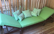 Green lounge chair with patterned pillows on a wooden deck at SunLodge Catalpa, Camping Cisano/San Vito, Italy.