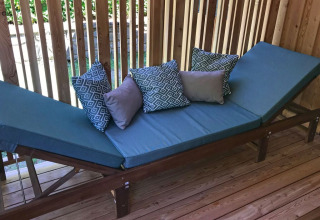 Cama de exterior con cojines azules y almohadas decorativas en SunLodge Catalpa, Camping Cisano/San Vito, Italia.