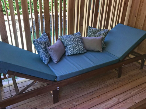 Cama de exterior con cojines azules y almohadas decorativas en SunLodge Catalpa, Camping Cisano/San Vito, Italia.