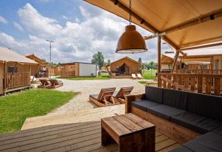 Vista desde la terraza de una tienda safari con muebles de madera en Camping Terme Catez, Eslovenia.