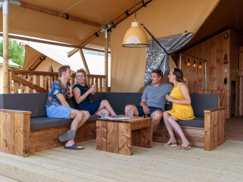 Four people relaxing in a SunLodge Pamoja&Kambi safari tent at Camping Terme Catez, Slovenia, enjoying drinks.