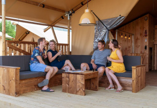 Cuatro personas disfrutan bebidas en una tienda safari SunLodge Pamoja&Kambi en Camping Terme Catez, Eslovenia.