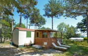 SunLodge Aspen in Camping Village Mare Pineta, Italië, met terras, ligstoelen en omgeven door pijnbomen.