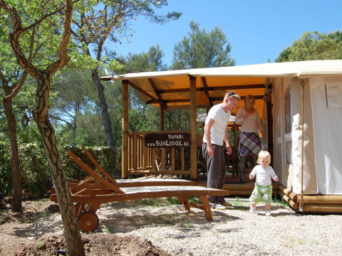 Familia disfruta al aire libre frente a la tienda SunLodge Safari en Camping Leï Suves, rodeada de árboles en Francia.