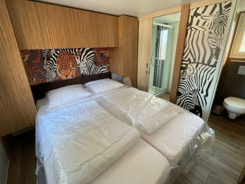 Slaapkamer in SunLodge Babul op Camping Pra'delle Torri in Italië met dierenmotief en eigen badkamer.