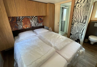 Slaapkamer in SunLodge Babul op Camping Pra'delle Torri in Italië met dierenmotief en eigen badkamer.