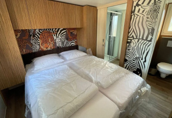 Camera da letto della SunLodge Babul al Camping Pra'delle Torri in Italia con arredo a tema animale e bagno.
