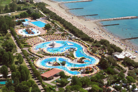 Vista aérea de un resort con parque acuático, piscinas, sombrillas y acceso directo a la playa.