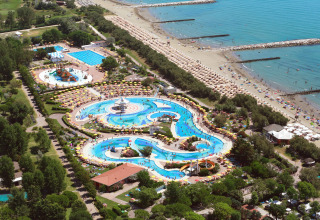 Vista aérea de un resort con parque acuático, piscinas, sombrillas y acceso directo a la playa.