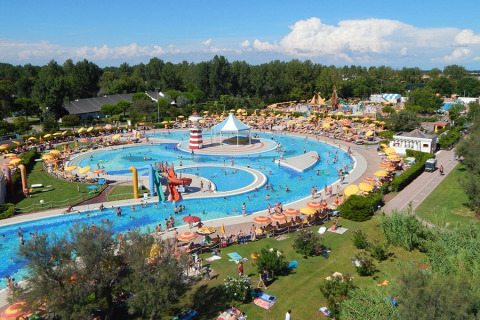 Luchtfoto van een populair waterpark aan een lodge, vol zwembaden, glijbanen en kleurrijke parasols.