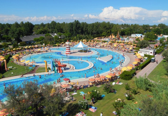 Aerial view of a busy water park at a lodge, featuring pools, water slides, and colorful umbrellas.