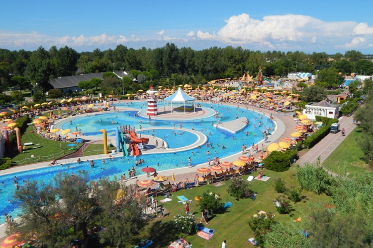 Aerial view of a busy water park at a lodge, featuring pools, water slides, and colorful umbrellas.