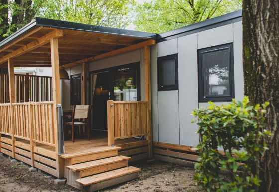 Udendørsbillede af SunLodge Babul, en moderne lodge med træterrasse, omgivet af grønne træer.