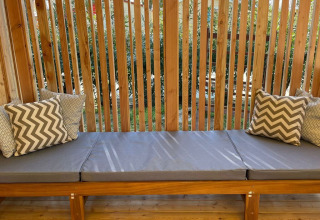 Zitbank met grijze kussens en houten lattenwand bij SunLodge Babul lodge.