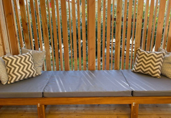 Panca imbottita con cuscini decorativi e grata in legno nella lodge SunLodge Babul.
