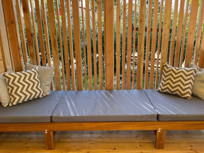 Padded outdoor bench with patterned cushions and wooden slats at SunLodge Babul lodge.
