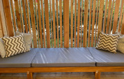 Banco exterior con cojines grises y estampados, detrás de listones de madera en SunLodge Babul.