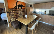 Comedor y cocina en SunLodge Babul con decoración de safari, estampados de animales y muebles de madera.