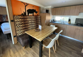 Coin repas et cuisine de la SunLodge Babul avec décor safari, motifs animaliers et mobilier en bois.