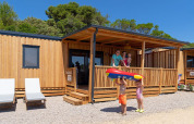 Famiglia felice davanti alla SunLodge BigLeaf al Camping Village Poljana in Croazia, con bambini e gonfiabile.