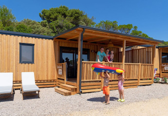 Famiglia felice davanti alla SunLodge BigLeaf al Camping Village Poljana in Croazia, con bambini e gonfiabile.