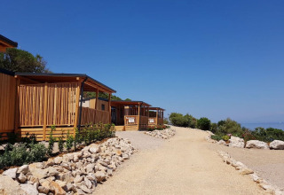 Cabanes SunLodge BigLeaf au Camping Village Poljana, Croatie, le long d’un chemin de graviers près de la mer.