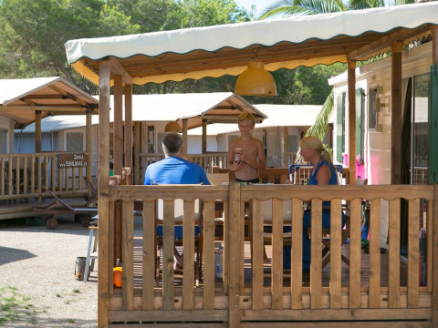 Gezin geniet op het terras van een SunLodge Maple cabin bij Camping Vilanova Park in Spanje.